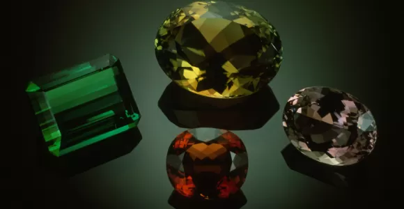 four colorful (green, yellow, red, and pink) gems on black background 