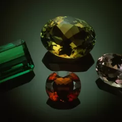 four colorful (green, yellow, red, and pink) gems on black background 