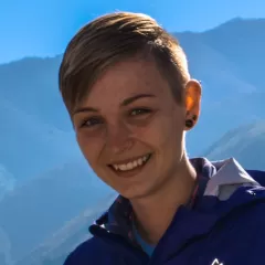 Woman in blue windbreaker in front of a mountain range