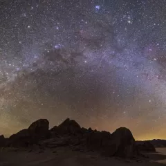 a bright halo of stars over a dark landscape 