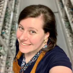 A smiling woman standing in front of jars of preserved museum specimens