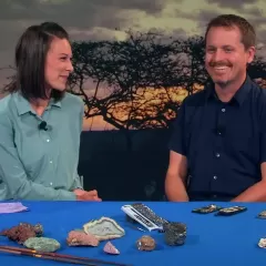 Maggy Benson and Dr. Joshua A. Bell sit at a table with several cell phones and various rocks and shells. 