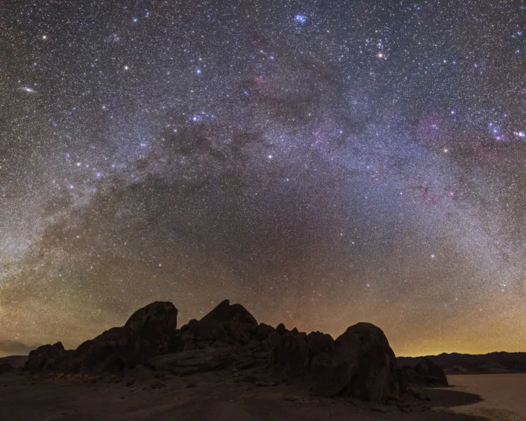 a bright halo of stars over a dark landscape 