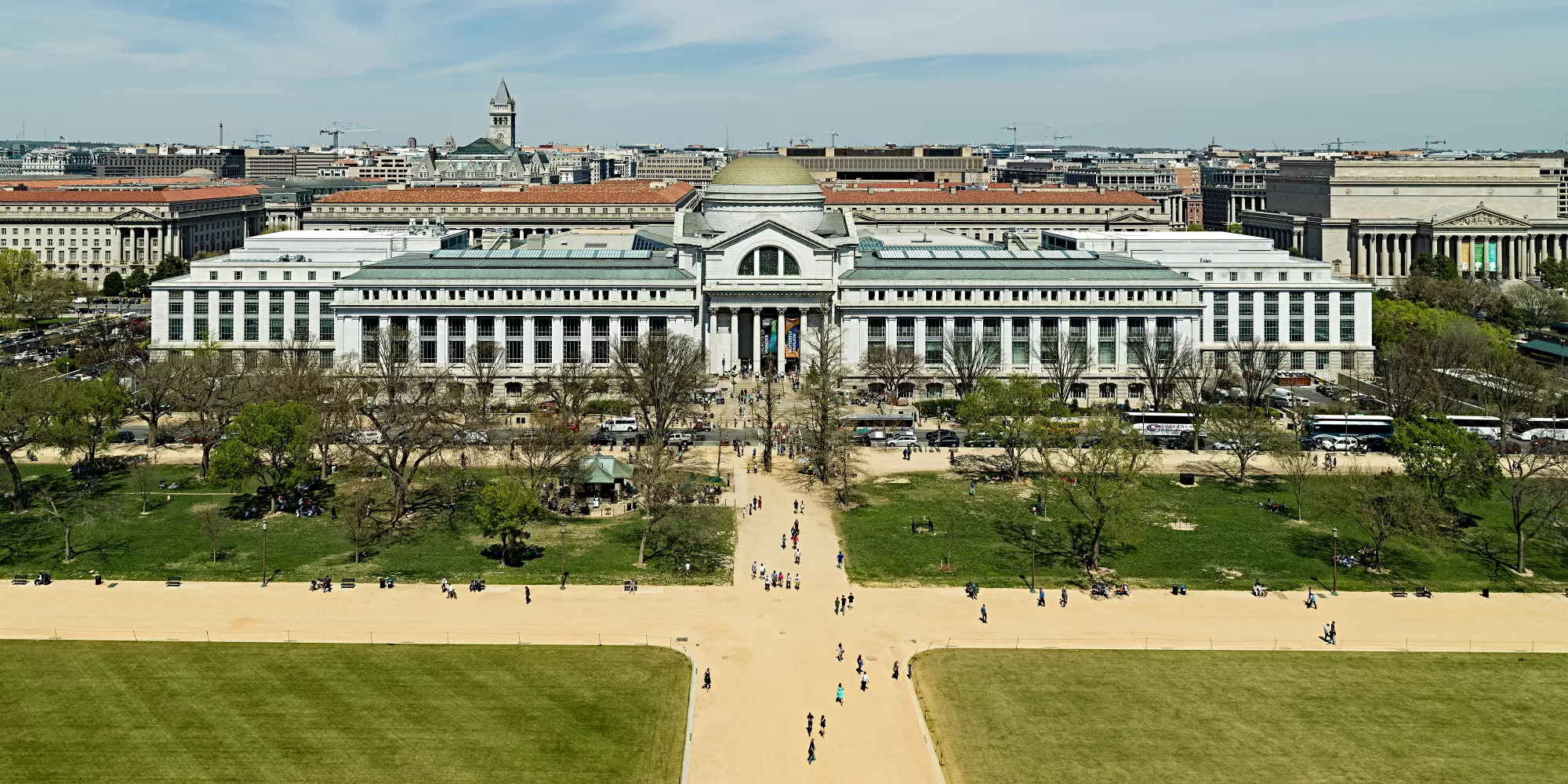 Aerial view from the National Mall of the National Museum of Natural History with its Gold Dome, wispy clouds, and DC in the background..