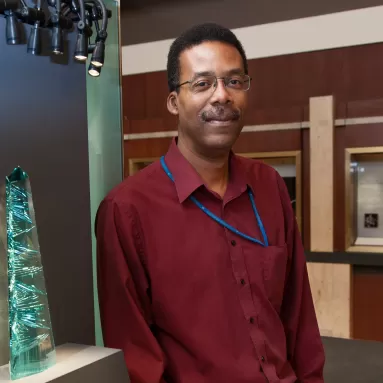 Man in red shirt stands next to aquamarine obelisk