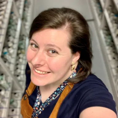 A smiling woman standing in front of jars of preserved museum specimens