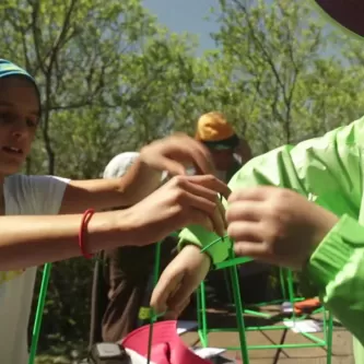 Two children building a biocube out of green aluminum tubing and green electrical wire.