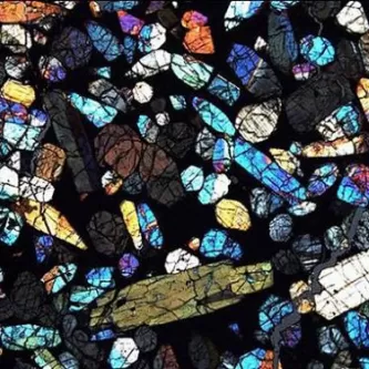 Brilliant mix of shapes colors like stained glass of a thin section of Antarctic meteorite.