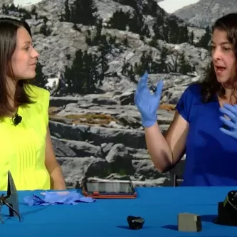 Maggy Benson and Dr. Cari Corrigan sitting at a table with rocks and pick..