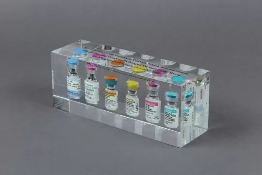 Transparent plastic box with six vaccine vials in it.