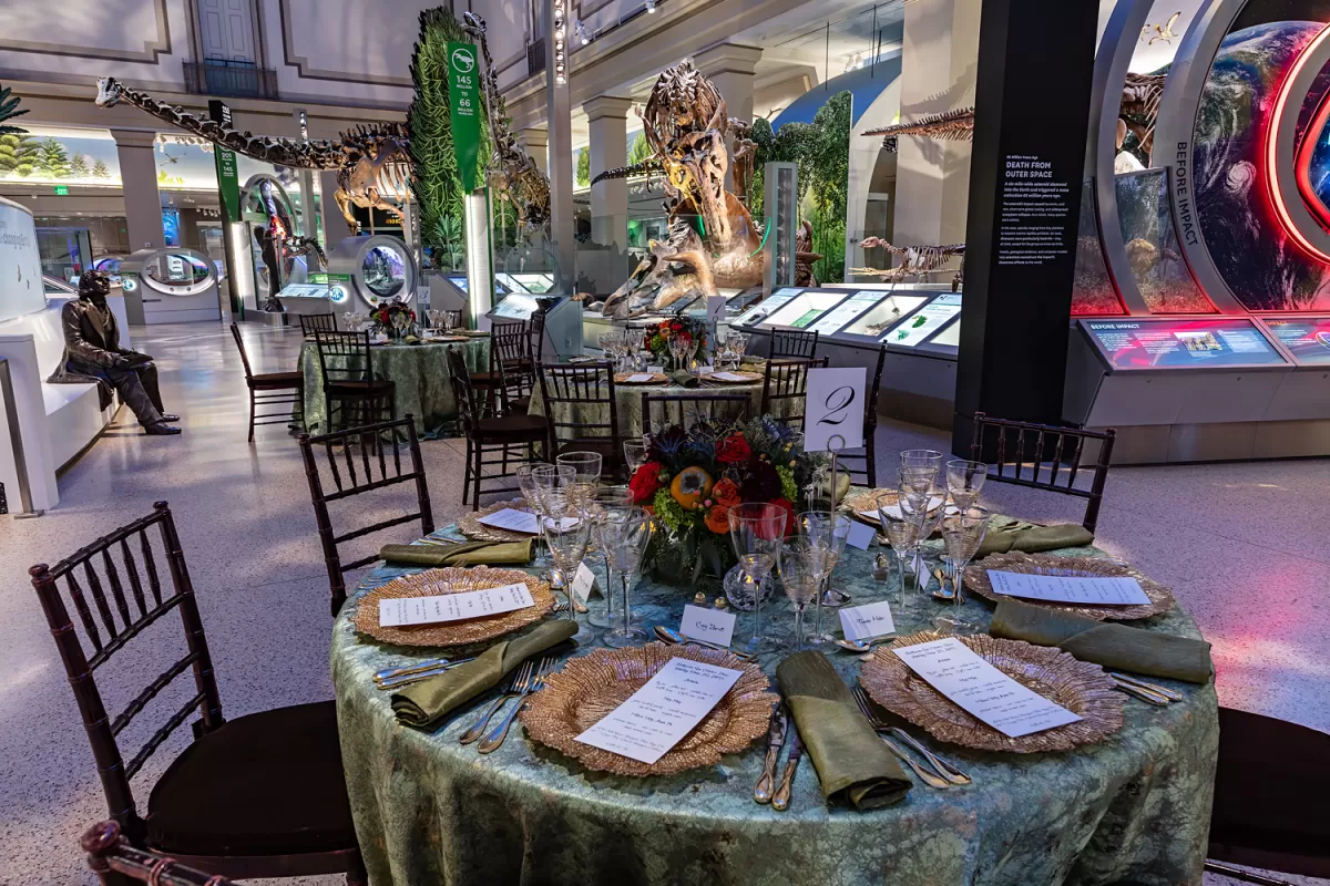 Tables set for dinner in the fossil hall with green tablecloths. 