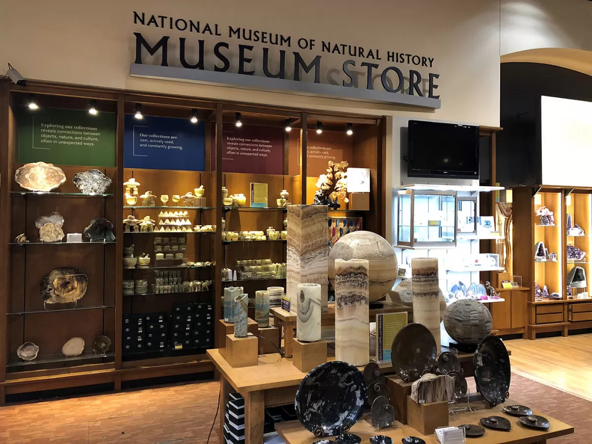 Items for sale, such as plates, bowls and decorations made from various minerals, all displayed on adjacent wooden tables. 