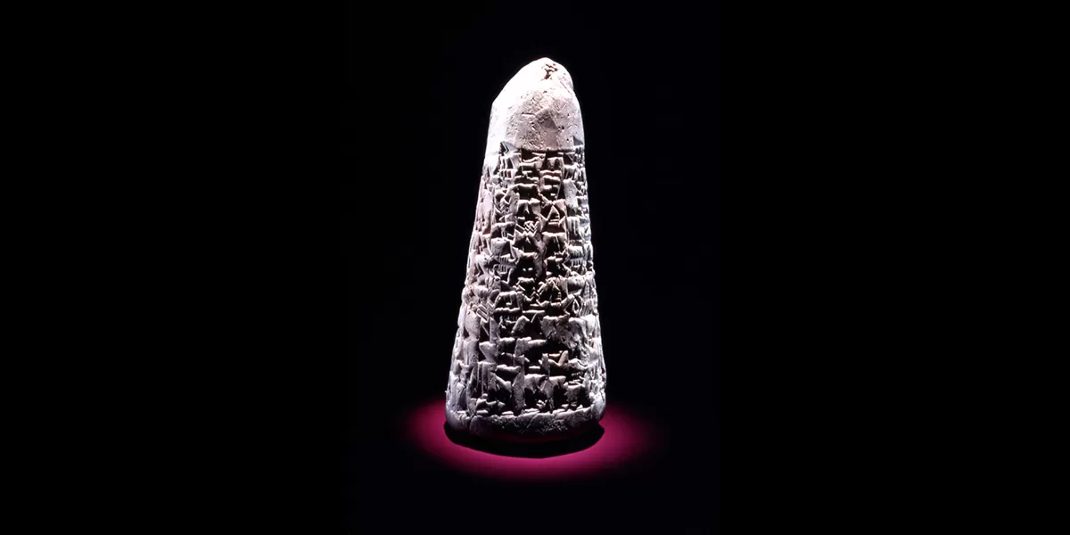 A gray, clay cone with cuneiform inscriptions covering most of it